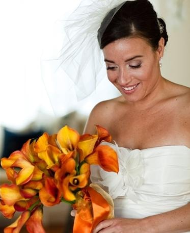 Toni Rigdon client — radiant bride gazing at vibrant orange calla lily bouquet